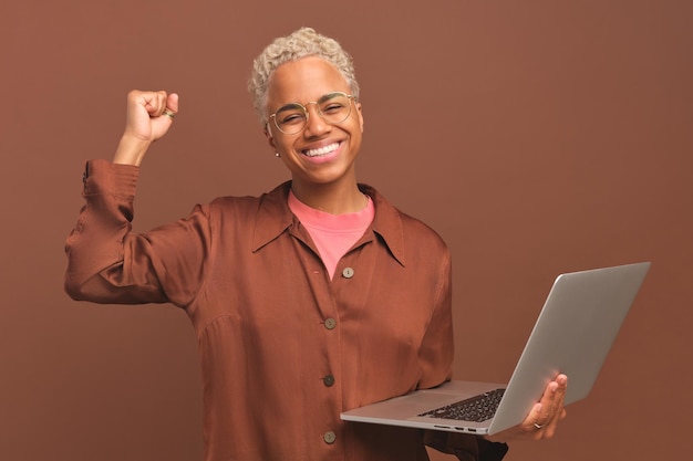 Une jeune femme afro-américaine ravie fait un geste de victoire et sourit