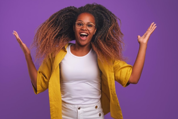 Une jeune femme afro-américaine ravie saute et crie dans un studio violet