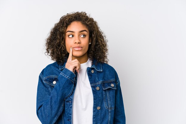 Jeune femme afro-américaine à la recherche sur le côté avec une expression douteuse et sceptique.