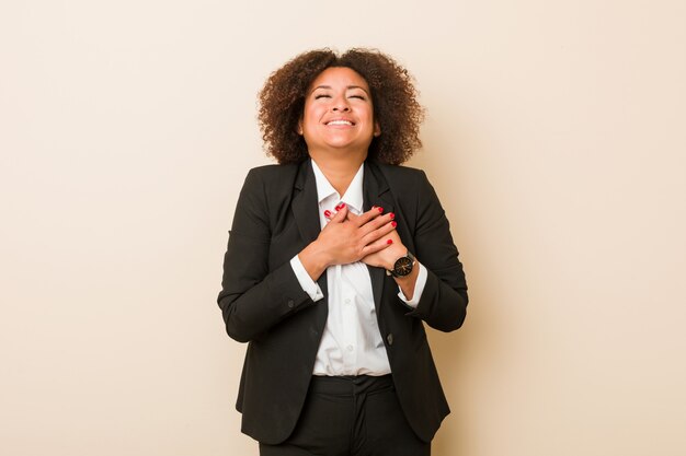 Jeune femme afro-américaine en riant en gardant les mains sur le cœur, le concept du bonheur.