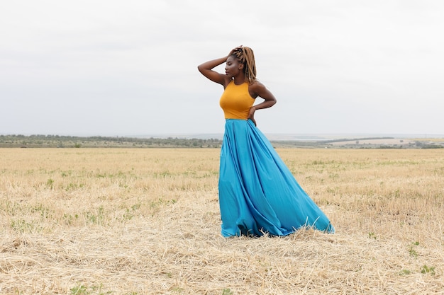 Jeune femme afro-américaine s'amusant à l'extérieur au coucher du soleil. fille qui rit sur le terrain. belle jeune femme afro-américaine avec des nattes