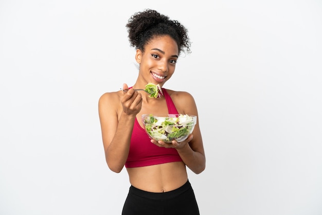 Jeune femme afro-américaine avec salade isolée sur fond blanc tenant un bol de salade avec une expression heureuse