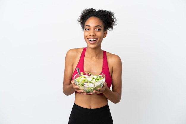 Jeune femme afro-américaine avec salade isolée sur fond blanc tenant un bol de salade avec une expression heureuse