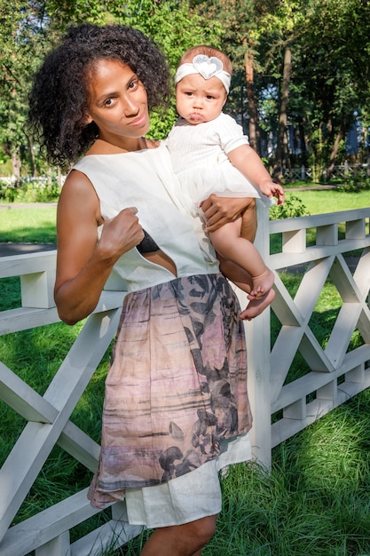 Jeune femme afro-américaine se préparant à allaiter son bébé dans le parc de l'été.