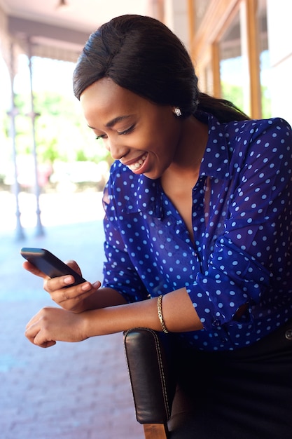 Jeune femme afro-américaine, souriant avec téléphone portable