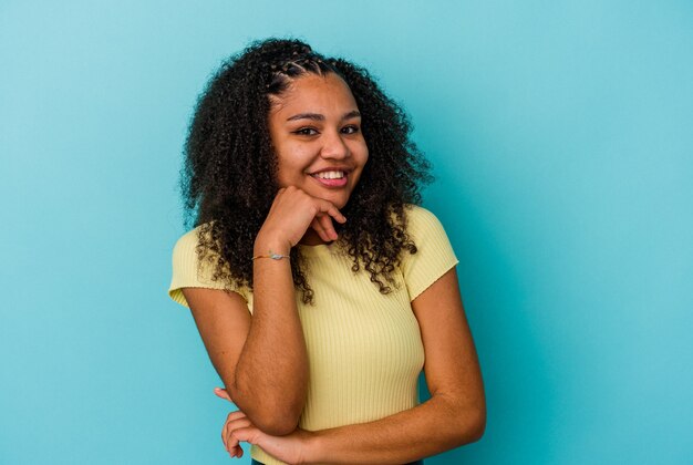 Jeune femme afro-américaine souriante heureuse et confiante, touchant le menton avec la main.