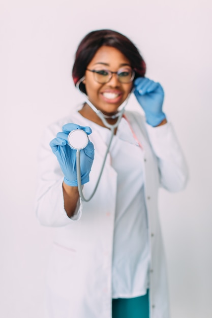 Jeune femme afro-américaine souriante médecin en blouse blanche tenant un stéthoscope