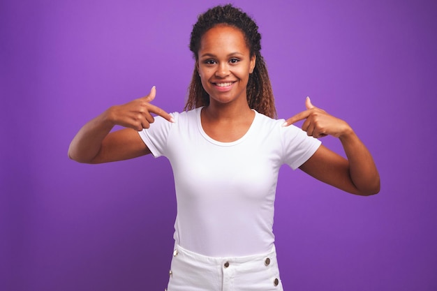 Jeune femme afro-américaine sourit et pointe du doigt le chemisier blanc comme neige