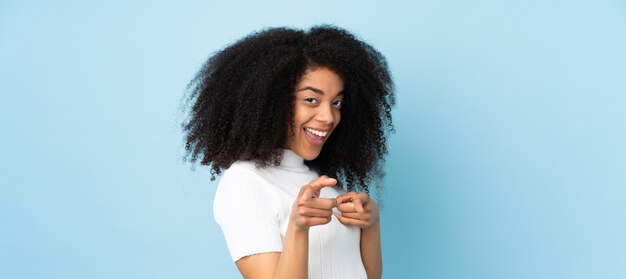 Jeune femme afro-américaine surprise et pointant vers l'avant