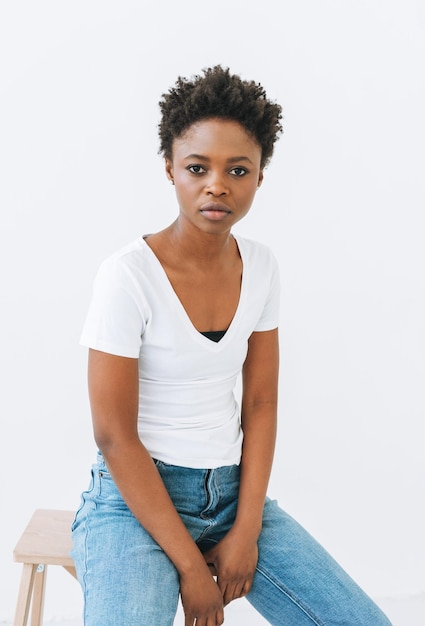 Jeune femme afro-américaine en t-shirt blanc et jeans bleu isolé sur fond blanc