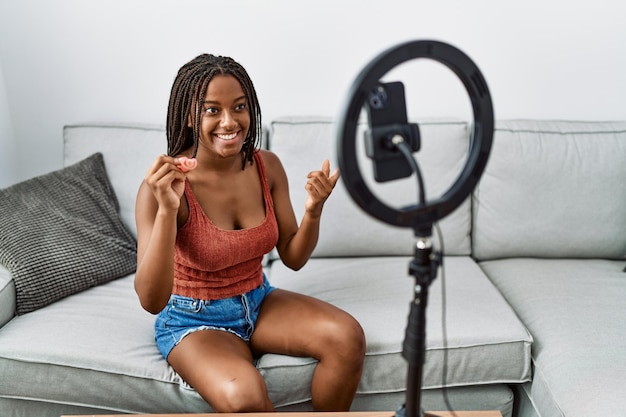 Jeune femme afro-américaine tenant une coupe menstruelle enregistrant un didacticiel vidéo à la maison