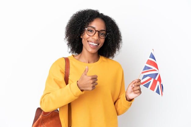 Jeune femme afro-américaine tenant un drapeau du Royaume-Uni isolé sur fond blanc donnant un coup de pouce geste