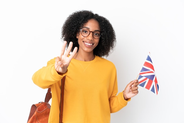 Jeune femme afro-américaine tenant un drapeau du Royaume-Uni isolé sur fond blanc heureux et comptant trois avec les doigts