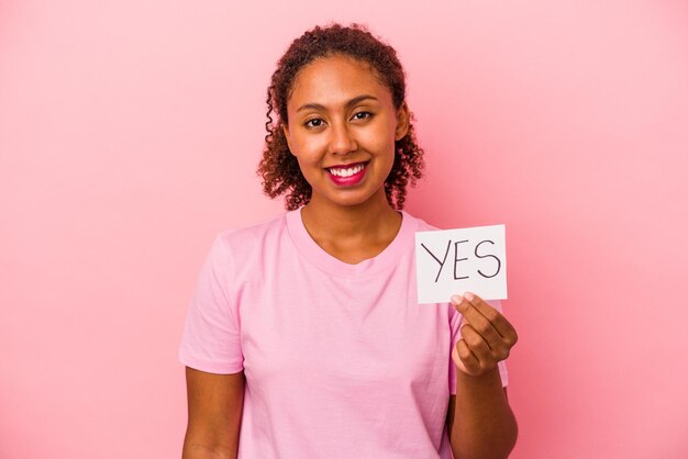 Jeune femme afro-américaine tenant une pancarte oui isolée sur fond rose