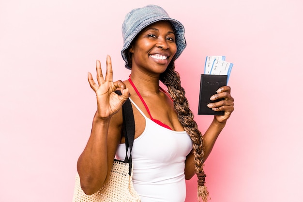 Jeune femme afro-américaine tenant un passeport isolé sur fond rose