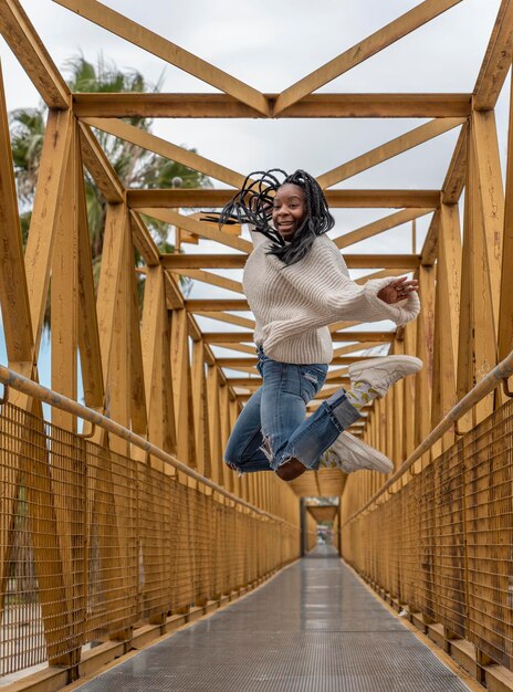 Une jeune femme afro-américaine avec des tresses sautant sur un pont jaune