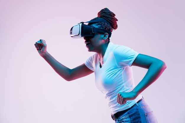 Jeune femme afro-américaine utilisant des lunettes VR à la lumière au néon