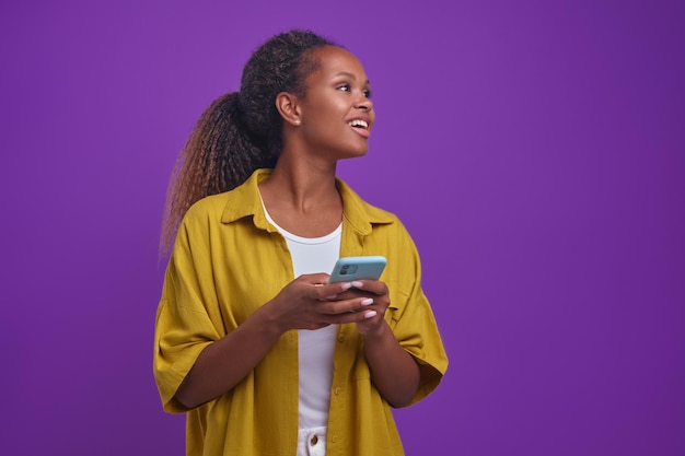 Une jeune femme afro-américaine utilise des applications de divertissement populaires avec son téléphone