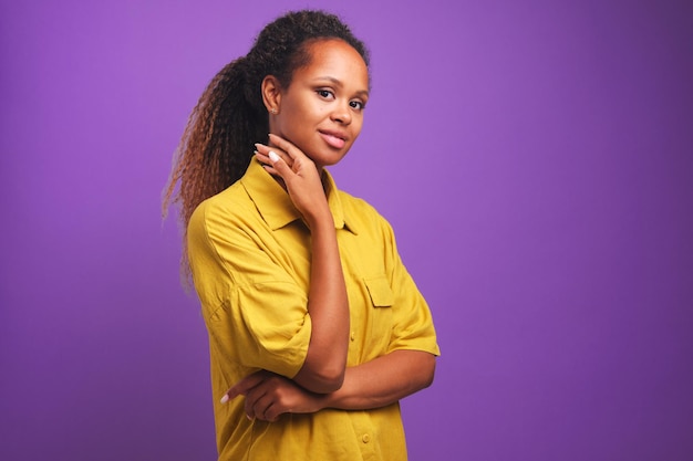 Jeune femme afro-américaine vous regarde en souriant légèrement touche le menton