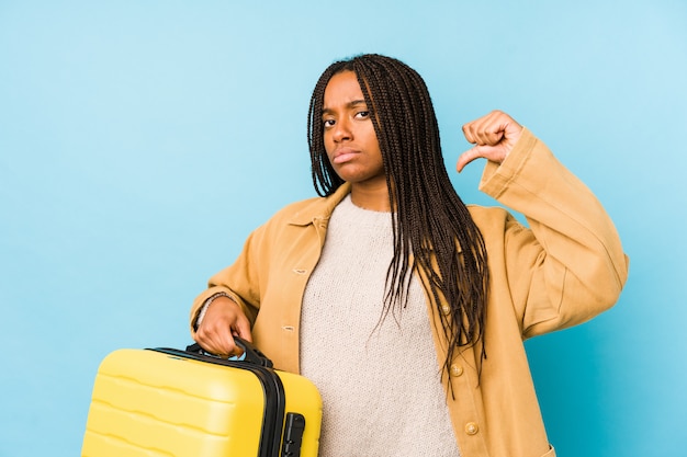 Jeune femme afro-américaine voyageur tenant une valise isolée se sent fière et sûre d'elle, exemple à suivre.