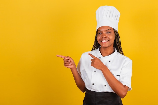 Jeune femme afro-brésilienne chef présentant quelque chose à gauche pointant vers quelque chose