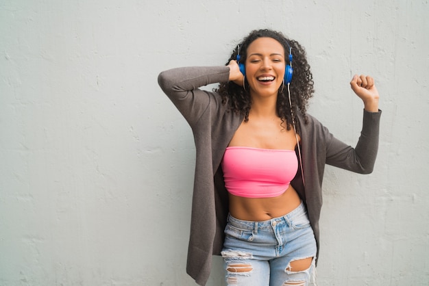 Jeune femme afro, écouter de la musique avec des écouteurs