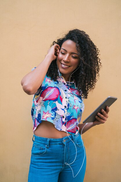 Jeune femme afro, écouter de la musique sur tablette.