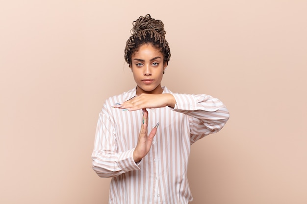 Jeune femme afro à la grave, sévère, en colère et mécontent, faisant signe de temps