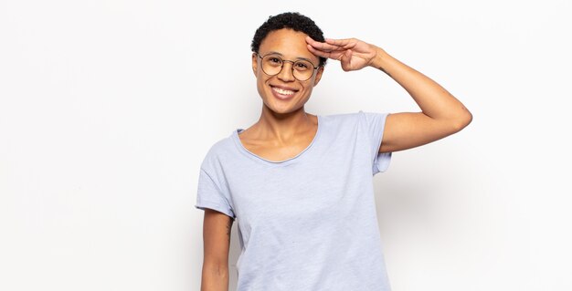 Jeune femme afro saluant l'avant avec un salut militaire dans un acte d'honneur et de patriotisme, montrant du respect