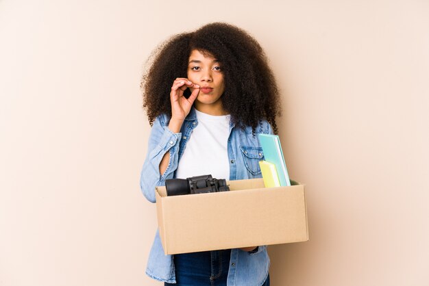 Jeune femme afro se déplaçant à la maison Jeune femme afro avec les doigts sur les lèvres gardant un secret.