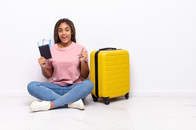 Jeune femme afro se sentant choquée, excitée et heureuse, riant et célébrant le succès, disant wow!. concept de vacances