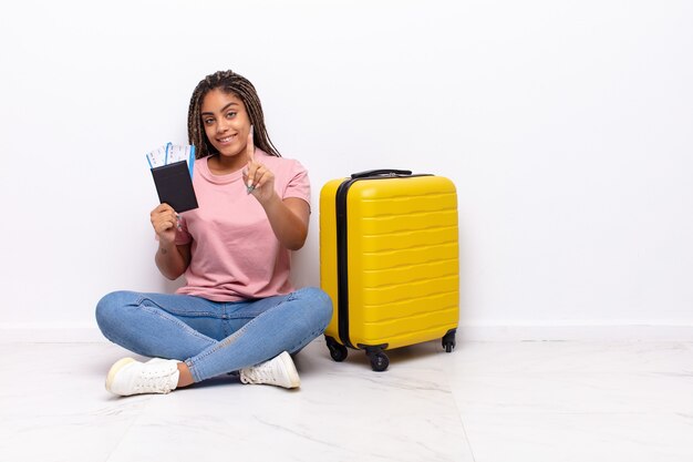 Jeune femme afro souriant fièrement et avec confiance, faisant la pose triomphante, se sentant comme un leader. concept de vacances