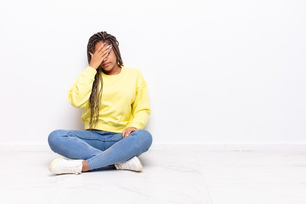 Jeune femme afro à stressé, honteux ou bouleversé, avec un mal de tête