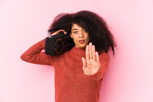 Photo jeune femme afro tenant une cassete debout avec la main tendue montrant le panneau d'arrêt