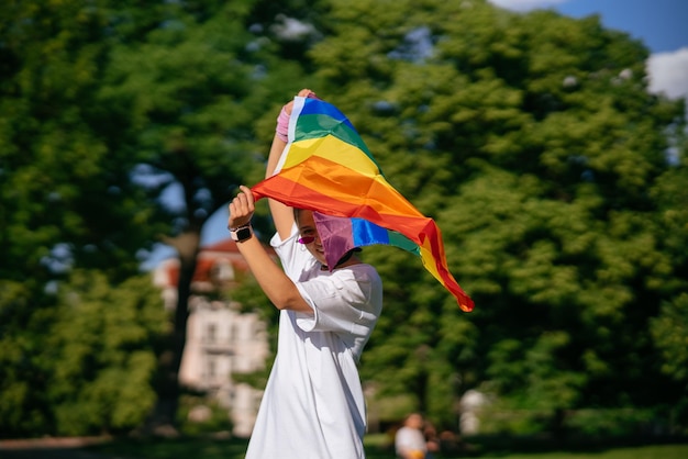 Jeune femme agitant le drapeau de la fierté LGBT dans le parc