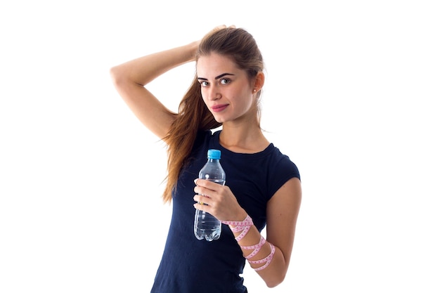Jeune femme agréable en T-shirt bleu avec un centimètre autour de sa taille ouvrant une bouteille d'eau