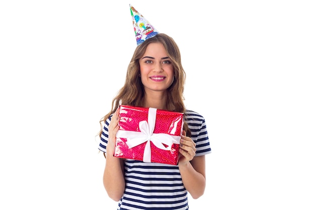 Jeune femme agréable en T-shirt dépouillé et casquette de célébration aux cheveux longs montrant un cadeau rouge