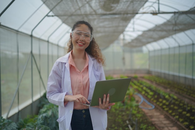 Jeune femme agronome tenant une usine de légumes de surveillance en serre