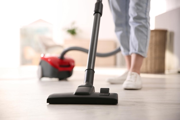 Jeune femme à l'aide d'un aspirateur à la maison agrandi