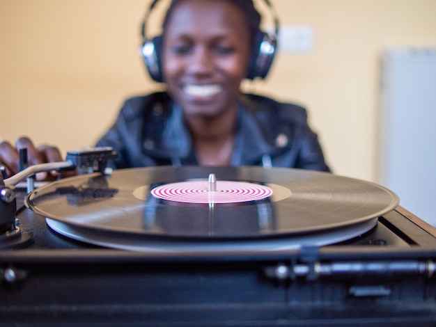 Jeune femme à l'aide d'écouteurs tout en jouant un disque vinyle sur une platine vintage