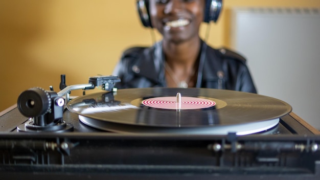 Jeune femme à l'aide d'écouteurs tout en jouant un disque vinyle sur une platine vintage