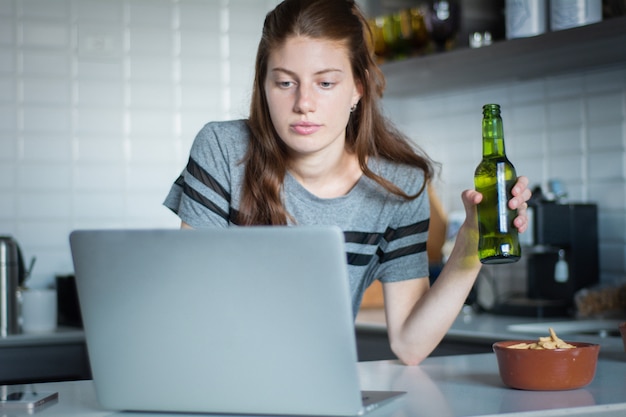 Jeune femme à l&#39;aide d&#39;un ordinateur portable avec un casque dans la cuisine