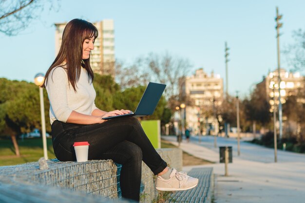 Jeune femme à l'aide d'un ordinateur portable dans la rue. Concept de travail indépendant.