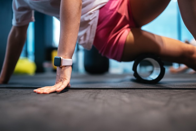 Jeune femme à l'aide d'un rouleau en mousse tout en faisant des exercices d'étirement