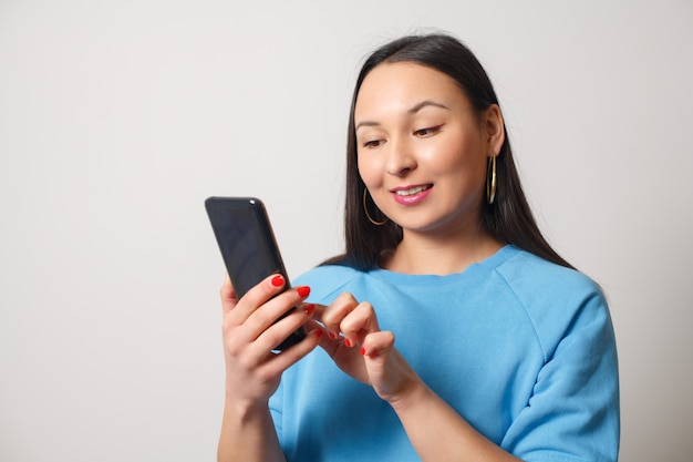 Jeune femme à l'aide d'un smartphone. Sur fond blanc.