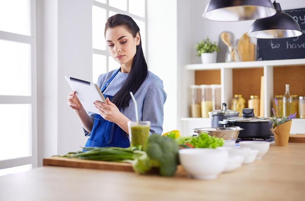 Jeune femme à l&#39;aide d&#39;une tablette PC pour cuisiner dans sa cuisine