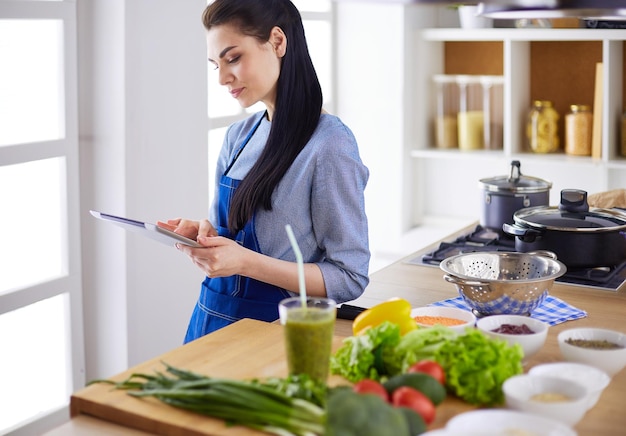 Jeune Femme à L'aide D'une Tablette Pc Pour Cuisiner Dans Sa Cuisine