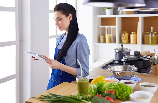 Jeune femme à l&#39;aide d&#39;une tablette PC pour cuisiner dans sa cuisine