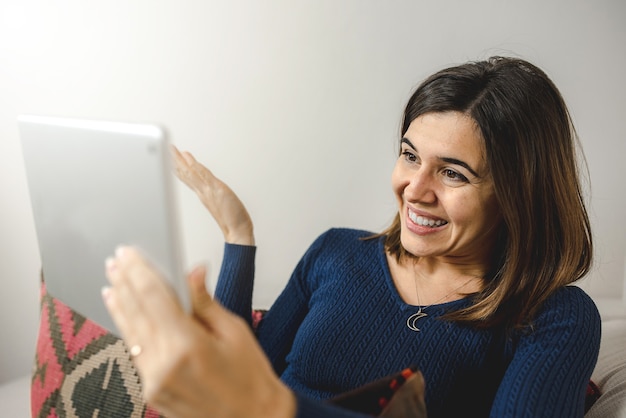 jeune femme à l'aide de tablette pour un appel vidéo à des amis ou à une famille, heureuse et souriante pendant la conversation.