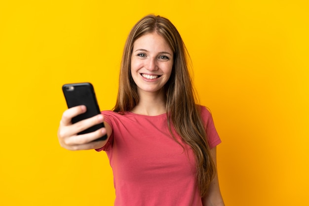 Jeune Femme à L'aide De Téléphone Mobile Isolé Sur Un Mur Jaune Avec Une Expression Heureuse